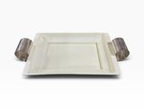 une assiette blanche munie d'une poignée métallique, posée sur une surface blanche