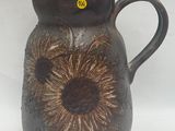 un vase marron orné d'une fleur, posé sur un fond blanc