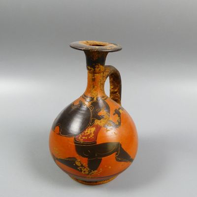 an orange vase with a black and gold design on it