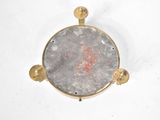 gold plated metal object with a stone in the center on a white surface