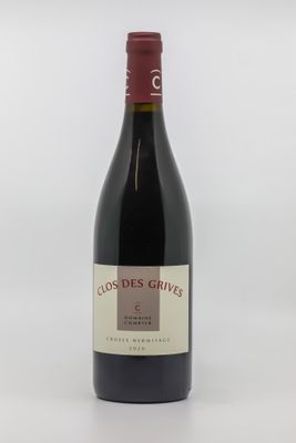 the bottle of red wine is sitting on a white surface