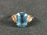 a close up of a gold ring with a blue topaz stone