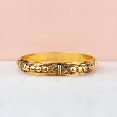 a close up of a gold bracelet on a white surface