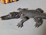 a statue of an alligator on a table next to a beaded necklace