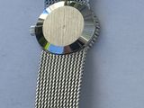 a close up of a watch with a metal band on a table