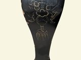 a black vase with a gold design on it