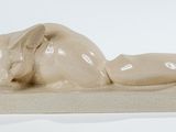une statue représentant un chat allongé sur un socle