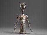 silver figurine of a man holding a knife in his right hand