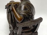 statue d'une femme assise sur une chaise en train de lire un livre
