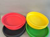 quatre assiettes de couleurs différentes posées sur une table blanche
