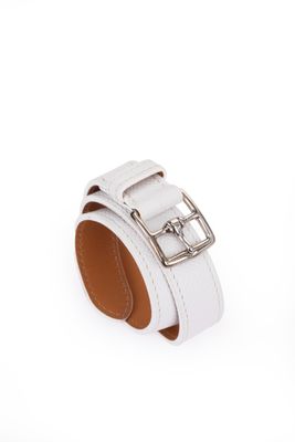 un gros plan sur un bracelet en cuir blanc muni d'une boucle en métal