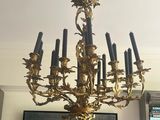 a gold chandelier with black candles in a living room
