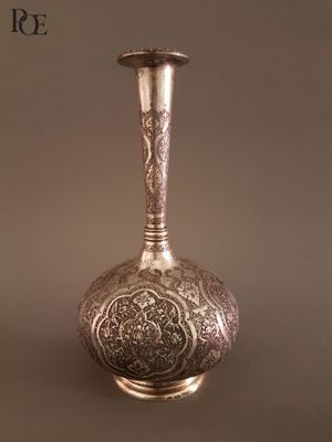 un vase en argent posé sur une table, sur fond marron