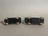 two pieces of black and gold metal are sitting on a table