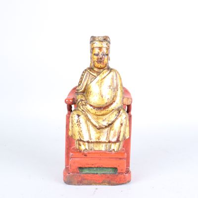 une petite statue représentant un homme assis sur une chaise rouge