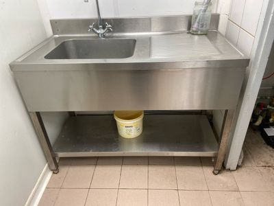 a stainless steel sink and a bucket on the floor
