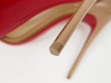 close up of a pair of red high heeled shoes on a white surface
