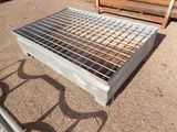 a metal grate sitting on the ground next to a pile of logs