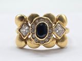 a close up of a gold ring with a blue stone surrounded by diamonds
