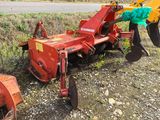 a red tractor plow sitting on the side of the road