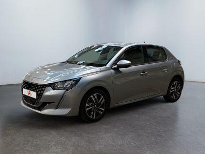 La voiture argentée est garée dans une pièce blanche au sol noir.