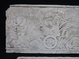 a stone relief of a man on a horse drawn carriage