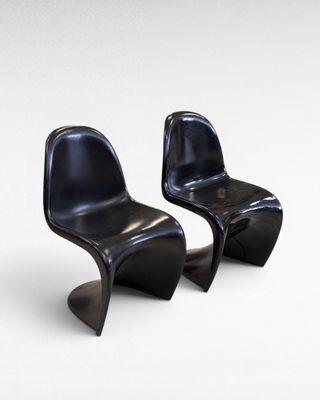 two black plastic chairs sitting side by side on a white surface