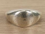 silver ring with a heart shaped design on top of a wooden surface
