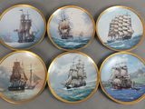 quatre assiettes ornées d'une peinture représentant des bateaux, posées sur une table