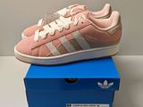 des baskets Adidas Superstar roses et blanches posées sur une boîte bleue