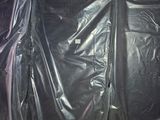 trois sacs en plastique noirs posés sur des palettes dans un entrepôt