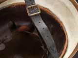 an old helmet with a leather strap hanging from it ' s side