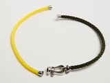 un gros plan sur un bracelet tressé jaune et noir muni d'un fermoir en argent