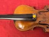 un vieux violon posé sur un tissu rouge, avec un archet dessus