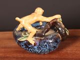 a figurine of a man sitting on top of a bowl on a table