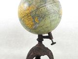 un petit globe posé sur un socle, sur une surface blanche