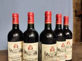 four bottles of red wine are lined up on a wooden table