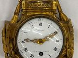 une horloge dorée accrochée au mur, avec des chiffres romains