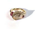 une image représentant une bague en or sertie d'une pierre à facettes entourée de rubis