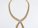 a gold and diamond necklace with a bow