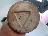 une main tenant un petit morceau de poterie sur lequel est dessiné un triangle
