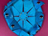 a picture of a blue origami clock on a pink surface