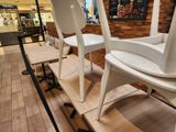 three white chairs sitting on a wooden bench in a store