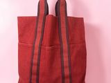 a red tote bag sitting on top of a pink surface