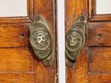 pair of antique wooden doors with metal handles and butterfly heads on them