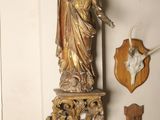 a statue of a woman on a shelf with deer heads on the wall