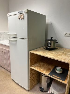 a small kitchen with a white refrigerator and a wooden counter