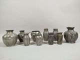 several silver vases are lined up in a row on a white surface
