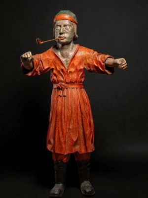 statue d'un homme vêtu d'une robe rouge, tenant une pipe et fumant une cigarette