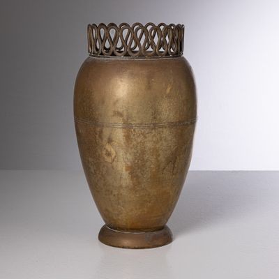 un vase doré posé sur une table blanche